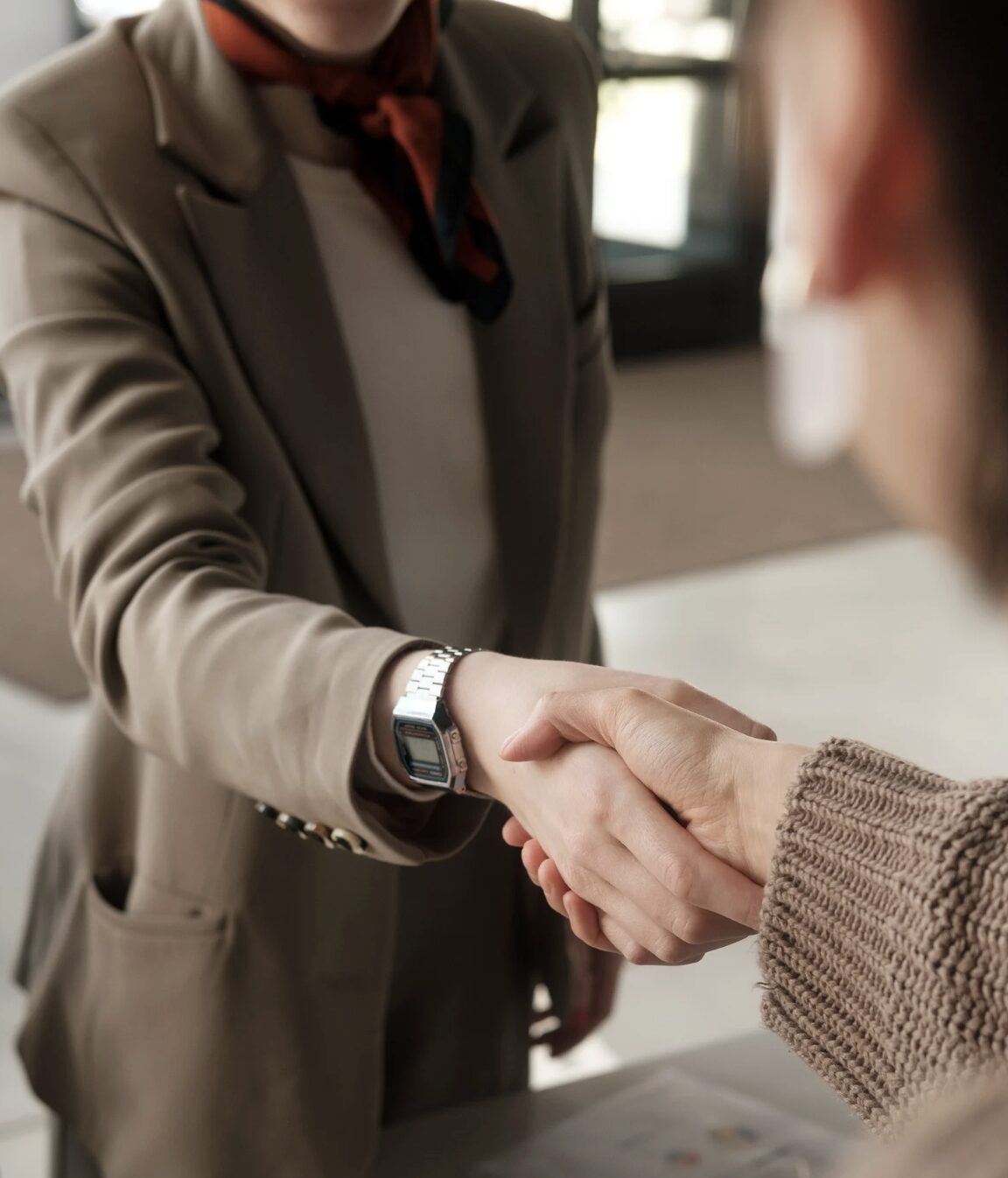 Woman in blazer shaking hands with someone.