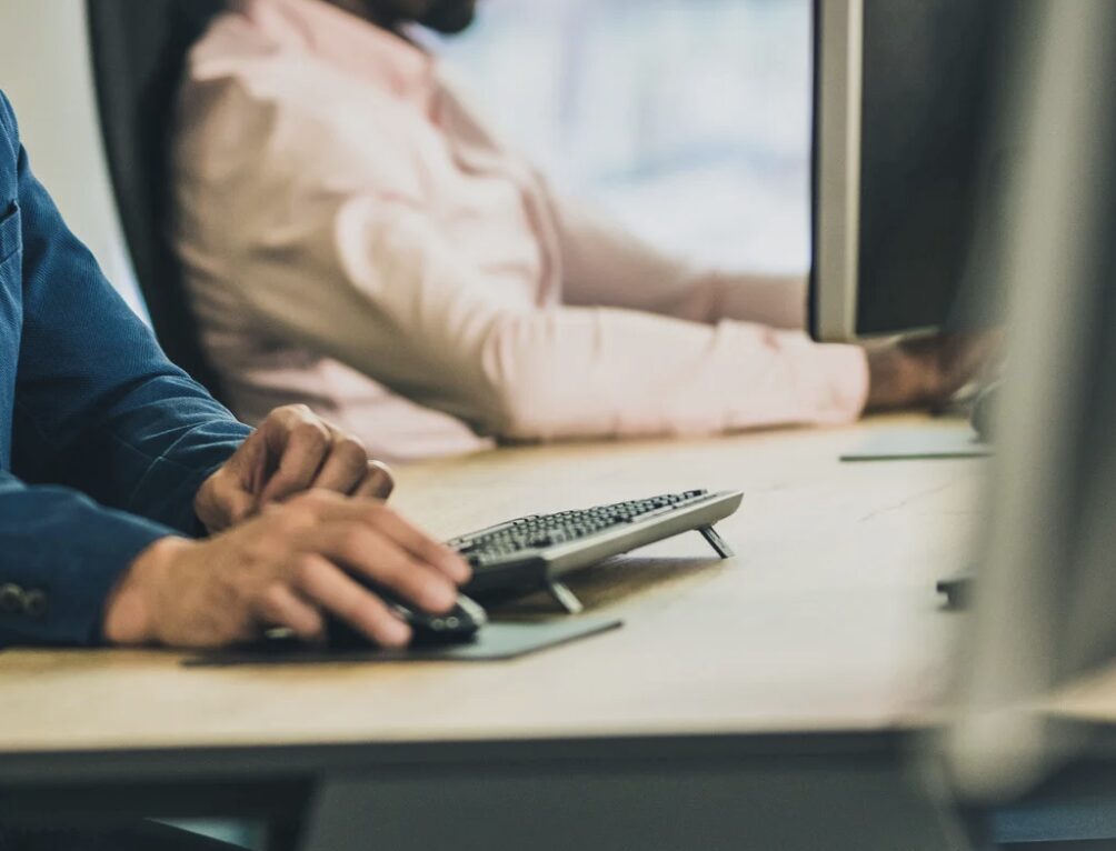 Two people working on Computer Management. Close up of people's hands working on a computer.